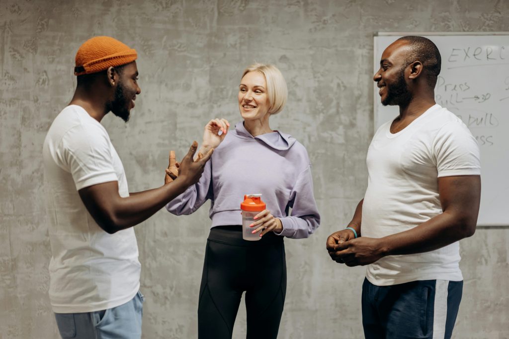 pexels-photo-6740302-6740302 Three adults having a lively discussion in an indoor gym setting.