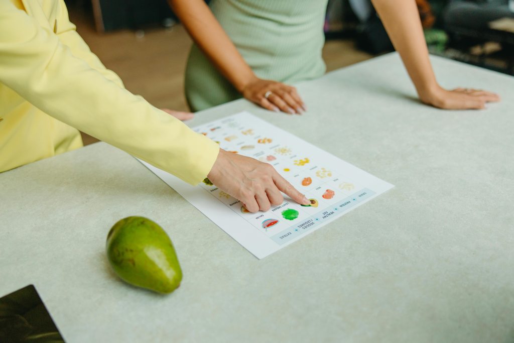 pexels-photo-8844379-8844379 Two adults discussing food options with a chart, highlighting healthy nutrition indoors.
