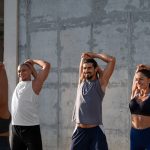 A group of people stretching outdoors in front of a large building, promoting fitness and wellness